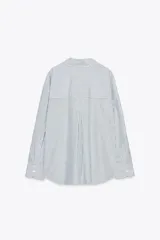 Camisa blanca con rayas verticales azul marino y lurex plateado, de corte recto, cuello solapa, escote en pico y cierre frontal con botones.