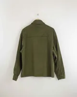 Camisa de pana color beige, de manga larga, con cuello camisero, cierre frontal de botones y dos bolsillos de parche con solapa en el pecho. Presenta un corte recto y holgado.