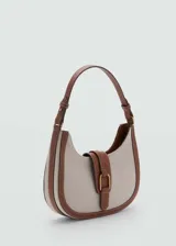 Bolso tipo hobo de lona color beige con detalles en cuero marrón. Tiene asa corta ajustable, cierre con solapa y botón magnético, bolsillo interior y forro de algodón.