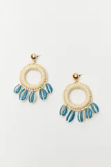 Par de aros colgantes con base circular de hilo color beige y apliques de conchillas pintadas de color azul.