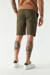 Bermuda de gabardina color beige, corte chino, con bolsillos laterales y traseros, cierre con cremallera y botón, presillas para cinturón y logo bordado.