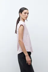 Remera de manga corta color rosa pálido, con cuello polo y escote en V con detalle de bordado en el borde.