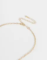 Collar corto dorado con cadena de eslabones, cierre de mosquetón y dijes colgantes de corazón, trébol de resina verde y herradura.