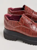 Mocasines color marrón con textura tipo piel de cocodrilo, detalle de calados en la parte delantera y plataforma track color negro.