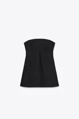 Vestido corto negro sin mangas, con escote palabra de honor y pespuntes marcados. Cierre trasero con cremallera oculta.