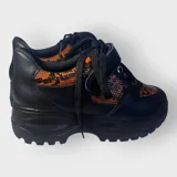 Zapatillas negras con detalles en animal print naranja y cordones negros.