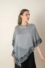 Blusa tipo poncho color gris con zócalo de tul bordado con motivos florales negros. Incluye una camiseta interior de spandex.