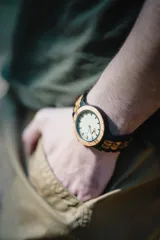 Reloj de pulsera con caja y esfera de madera clara, malla de madera oscura con incrustaciones de madera clara.