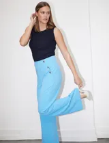 Pantalón largo de crepe elastizado color celeste, de corte recto, con bolsillos delanteros y apliques de botones metálicos. Marca One Five One.