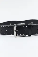 Cinturón negro de cuero sintético con hebilla metálica plateada y apliques de tachas plateadas con forma de corazón y circulares.