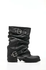 Bota de cuero negro con caña media arrugada, dos correas con hebillas plateadas y taco bajo.