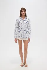 Camisa de manga larga con estampado de motivos playeros en tonos marrones sobre fondo beige, cuello camisero y cierre frontal con botones.