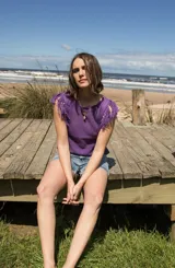 Musculosa tejida color marrón con diseño calado y flecos en los hombros.