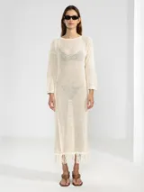 Vestido largo color crudo, tejido en punto abierto de algodón con lúrex y flecos en el ruedo.