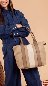 Cartera de mano color beige con divisiones y detalles en marrón y blanco. Tiene correa corta, correa larga ajustable, bolsillo trasero y bolsillos internos.