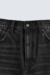 Bermuda de jean azul con lavado medio, corte holgado, cinco bolsillos, roturas y cierre frontal con cremallera y botón.