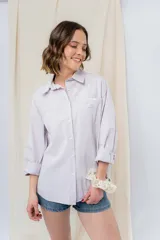 Camisa color crema de algodón liviano, calce oversize, con cuello camisero, cierre abotonado, mangas largas con opción de arremangado y dos bolsillos frontales con solapa.
