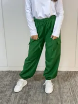 Pantalón babucha verde oliva de corte holgado, con cintura elástica, terminaciones elásticas en los tobillos y bolsillos cargo laterales.