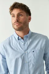 Camisa celeste a rayas rojas de hombre, manga larga, con bolsillo y logo bordado.