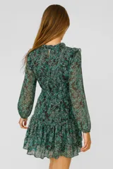 Vestido corto color verde con estampado floral, escote en V con borla, mangas largas abullonadas y falda escalonada con volantes.