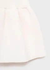 Top de punto fino color blanco hueso, sin mangas, con escote pronunciado en V y cierre frontal mediante lazos anudados. Presenta un tejido de canalé y un diseño ligeramente evasé en la parte inferior.