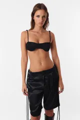 Conjunto de top y short color beige confeccionado en tela brillante. El top cuenta con arco metálico en el busto, tiras para atar en el hombro y ganchos lenceros en la espalda. El short es de tiro alto con cintura elastizada y bolsillos laterales.