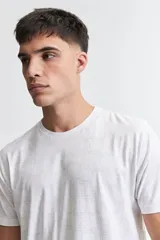 Remera blanca con estampado abstracto en tonos grises, de manga corta, corte regular y cuello redondo.