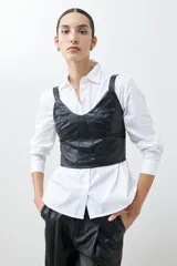 Top negro de eco cuero con corte crop, breteles finos y detalle de tul en el escote.