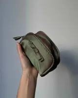 Neceser gris de tela satinada con cierre superior y detalle de moño en el frente.