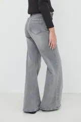 Jean de corte wide leg en color gris con lavado desgastado, tiro medio y cierre frontal con botón y cremallera.