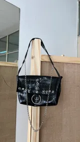 Cartera negra con textura símil cocodrilo, con herrajes plateados y cadena decorativa.