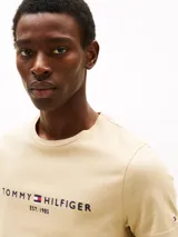 Remera color beige de algodón con cuello redondo y logo bordado de Tommy Hilfiger en el pecho.