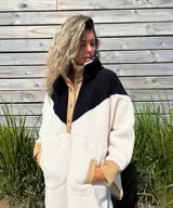 Buzo tipo poncho de polar color crudo con bloque superior en negro y detalles en beige.