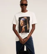 Remera de algodón color blanco, con cuello redondo y mangas cortas. Estampa frontal con la pintura "La joven de la perla" de Johannes Vermeer.