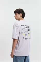 Remera color café de corte oversize con cuello redondo y mangas cortas. Estampado en la espalda con la frase "Stay Original Forever" y varios diseños gráficos.