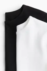 Pack de dos remeras cortas de algodón, una blanca y otra negra, con cuello redondo y corte ajustado.