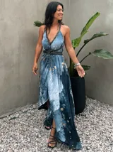 Vestido largo de tela fluida, color verde esmeralda con estampado abstracto en tonos turquesa y detalles dorados. Diseño asimétrico con un solo tirante tejido en el hombro.