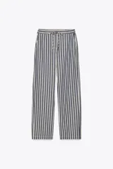 Pantalón de tiro medio con cintura elástica ajustable con cordones, bolsillos delanteros y traseros de parche. Pierna ancha con estampado de rayas verticales azules y blancas.