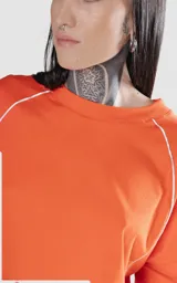 Remera corta naranja con mangas cortas abullonadas y ribete blanco en cuello, mangas y laterales.