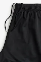 Short deportivo negro de tejido funcional de secado rápido con buena permeabilidad al aire. Cintura elástica con cordón para ajustar oculto, bolsillos en las costuras laterales y aberturas laterales en el bajo.