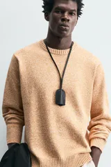 Sweater color arena con textura jaspeada, de corte recto, cuello redondo y mangas largas con terminaciones acanaladas.