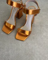 Sandalias plateadas con tira delantera, tobillera con hebilla y taco geométrico.