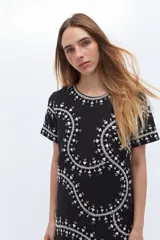 Remerón negro con bordado floral blanco, de corte recto y mangas cortas.