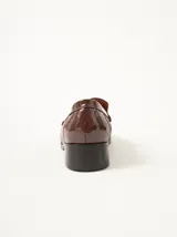 Mocasines de cuero color marrón con apliques de charol y pespuntes rojos.