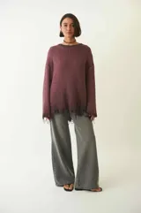 Sweater tejido color crudo, de manga larga con efecto desgastado y deshilachado en el ruedo y puños. Tiene cuello redondo y calce holgado.
