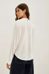 Camisa blanca de manga larga con cuello mao y escote en V, con bordados negros en el frente y puños.