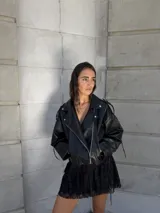 Campera negra de cuero sintético, estilo biker, con cierre cruzado y detalles de hebillas en los hombros.