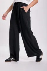 Pantalón negro de vestir de corte palazzo con cintura alta y lazo ajustable.