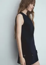 Vestido corto azul marino sin mangas, con cuello redondo, corte recto, botones decorativos en la parte inferior y cierre trasero invisible.