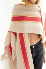 Ruana artesanal color beige con rayas horizontales rojas y amarillas, y flecos en el borde inferior.